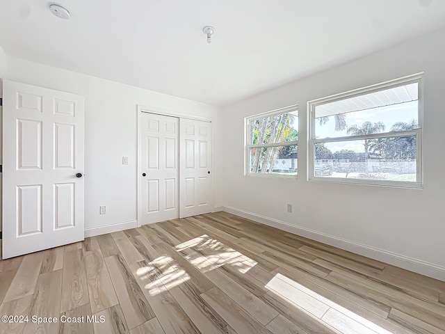 unfurnished bedroom with a closet and light hardwood / wood-style floors