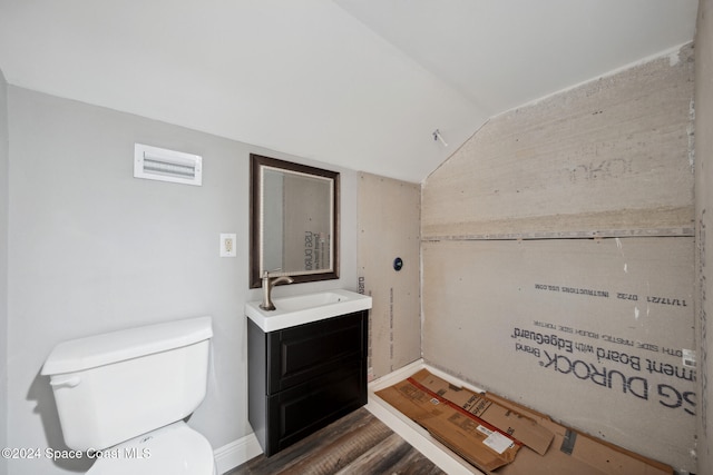 bathroom featuring vanity, lofted ceiling, wood-type flooring, and toilet