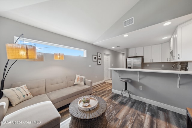 living room featuring dark hardwood / wood-style floors, sink, and vaulted ceiling