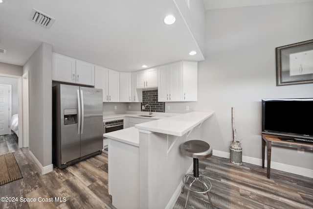 kitchen with kitchen peninsula, a breakfast bar area, stainless steel fridge with ice dispenser, white cabinetry, and dark wood-type flooring