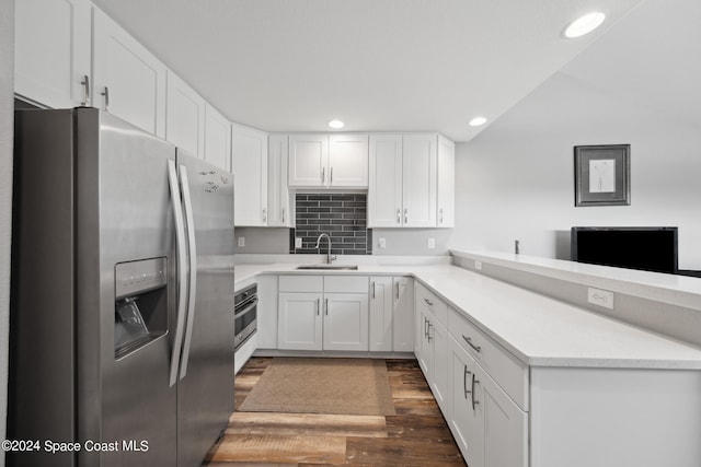 kitchen featuring appliances with stainless steel finishes, sink, white cabinets, decorative backsplash, and dark hardwood / wood-style floors