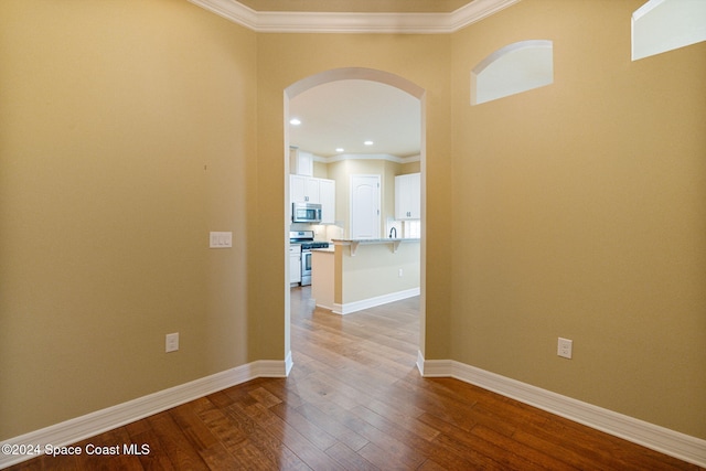 hallway with wood-type flooring and ornamental molding