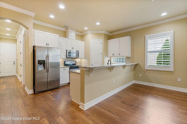 kitchen featuring white cabinets, dark hardwood / wood-style flooring, a kitchen bar, and appliances with stainless steel finishes