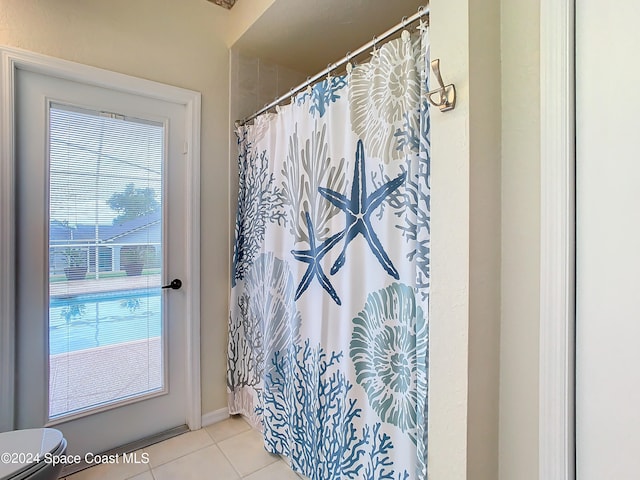 bathroom with toilet, curtained shower, and tile patterned flooring