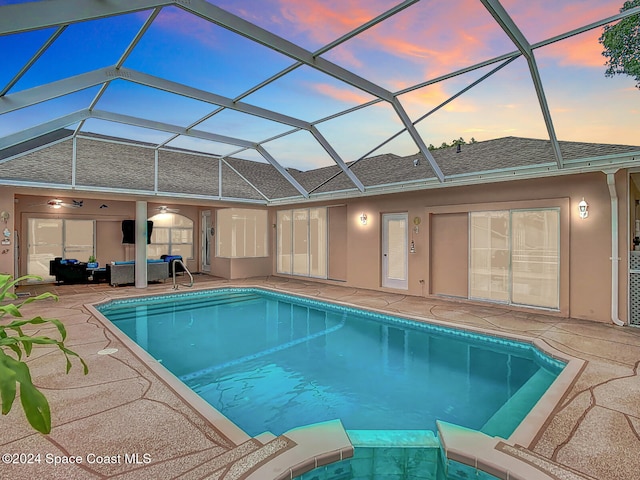 pool at dusk with a patio area and a lanai