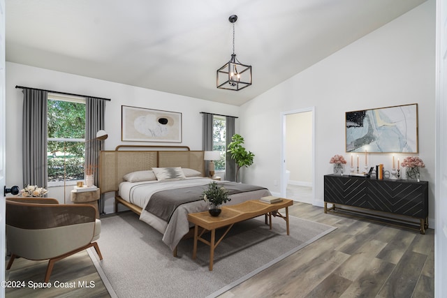 bedroom featuring connected bathroom, hardwood / wood-style floors, vaulted ceiling, and multiple windows