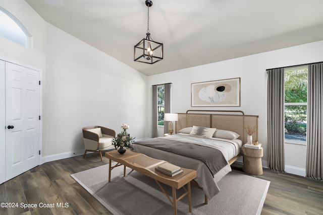 bedroom with lofted ceiling, a chandelier, and dark hardwood / wood-style flooring