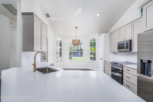 kitchen featuring hanging light fixtures, backsplash, appliances with stainless steel finishes, vaulted ceiling, and sink