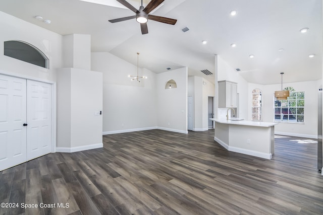 unfurnished living room with high vaulted ceiling, sink, ceiling fan with notable chandelier, and dark hardwood / wood-style flooring