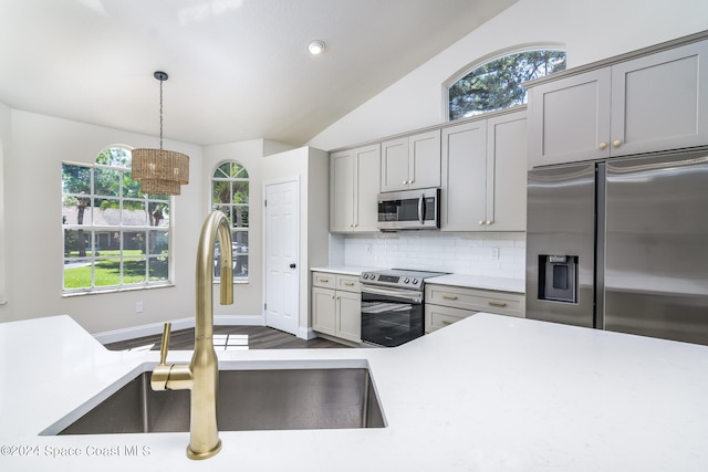 kitchen with a healthy amount of sunlight, appliances with stainless steel finishes, sink, and lofted ceiling