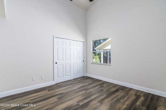 unfurnished bedroom featuring a towering ceiling, dark hardwood / wood-style floors, and a closet