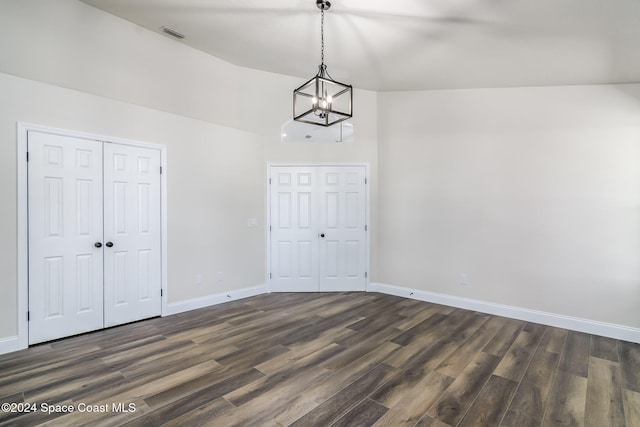 interior space with dark wood-type flooring, a notable chandelier, and lofted ceiling