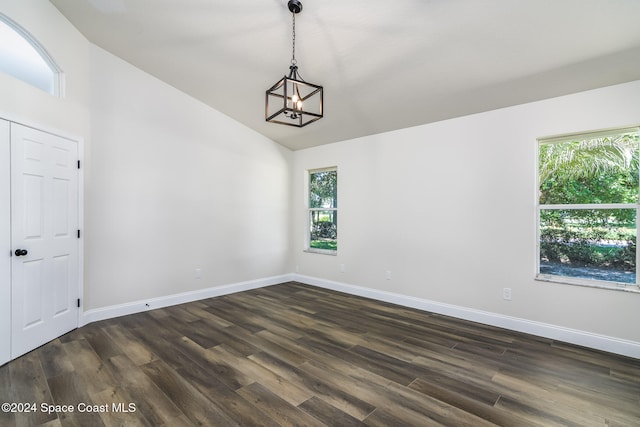 unfurnished room featuring a chandelier, vaulted ceiling, dark hardwood / wood-style floors, and plenty of natural light