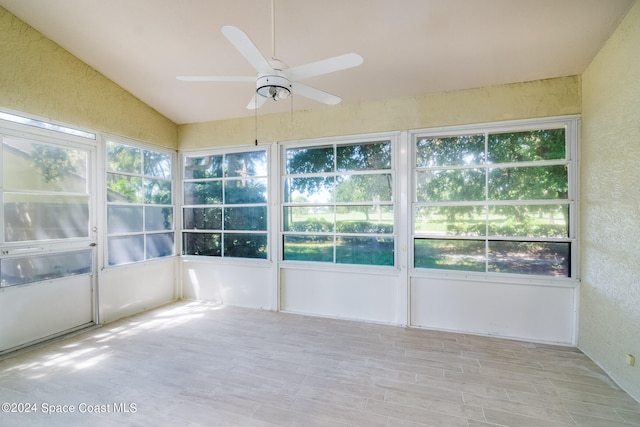 unfurnished sunroom with a wealth of natural light, lofted ceiling, and ceiling fan