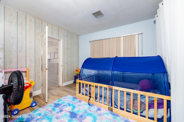 bedroom featuring light wood-type flooring and wooden walls