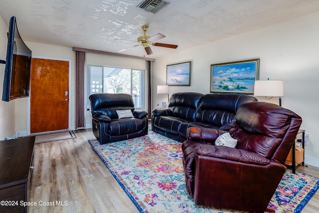 living room featuring ceiling fan, hardwood / wood-style floors, and a textured ceiling