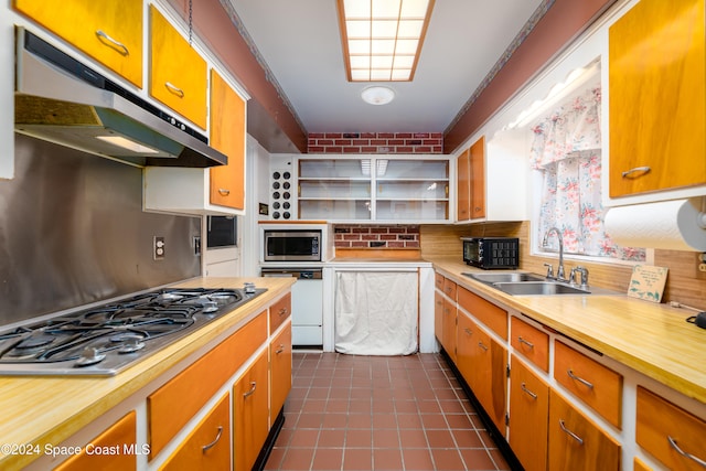 kitchen with backsplash, stainless steel appliances, crown molding, sink, and dark tile patterned flooring