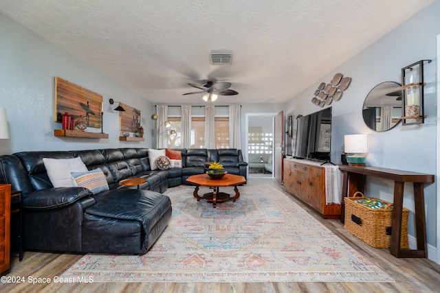 living room featuring a textured ceiling, light hardwood / wood-style floors, and ceiling fan