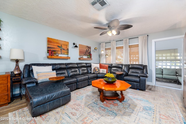 living room featuring wood-type flooring, a textured ceiling, and ceiling fan