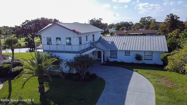 view of front of home with a balcony and a front lawn