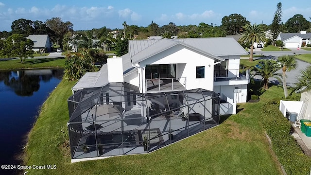 rear view of property featuring a yard, a water view, and glass enclosure