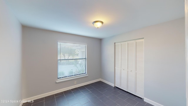 unfurnished bedroom featuring a closet and dark tile patterned floors