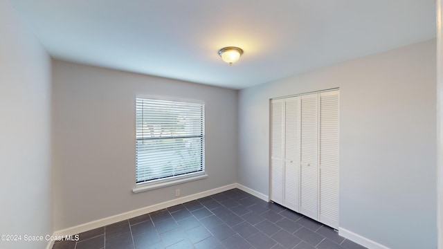 unfurnished bedroom featuring dark tile patterned floors and a closet