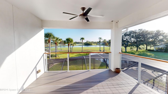 wooden terrace with a water view, a lawn, and ceiling fan