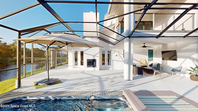 exterior space featuring french doors, a patio, a lanai, ceiling fan, and a water view