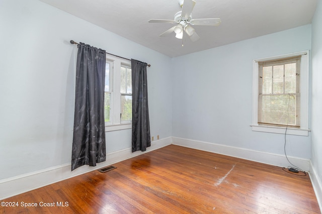 empty room featuring wood-type flooring, a healthy amount of sunlight, and ceiling fan