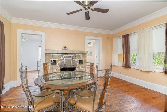 dining area with ceiling fan, crown molding, a fireplace, and hardwood / wood-style floors