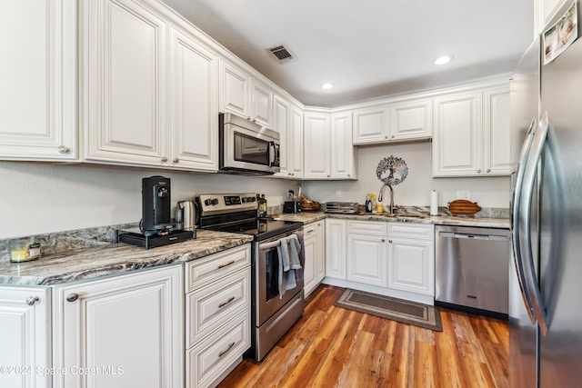 kitchen with sink, white cabinetry, stainless steel appliances, and light wood-type flooring