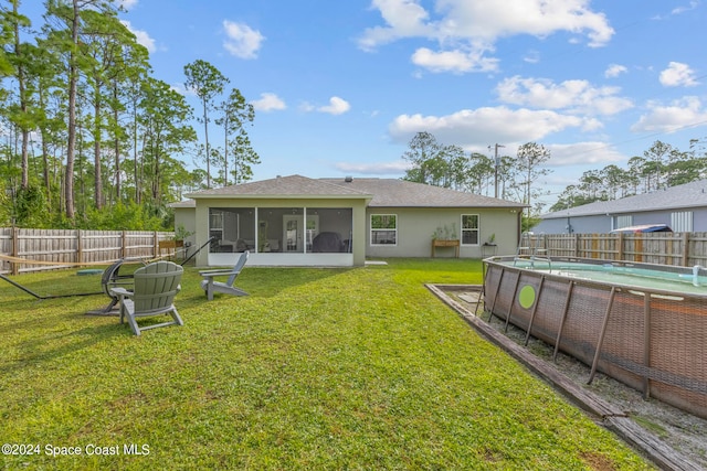 rear view of property featuring a fenced in pool, a lawn, and a sunroom