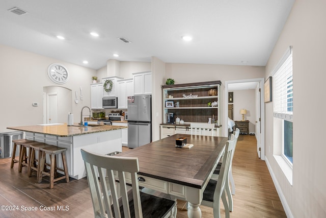 dining room featuring sink, lofted ceiling, and hardwood / wood-style floors