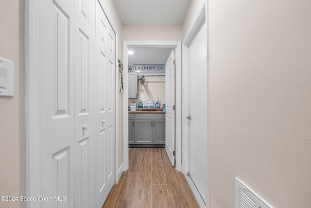 corridor with light hardwood / wood-style flooring and sink