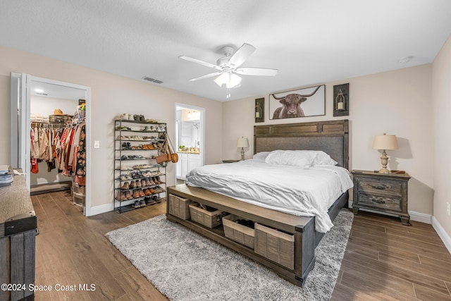 bedroom featuring ceiling fan, dark hardwood / wood-style flooring, connected bathroom, a closet, and a walk in closet