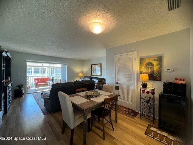 dining space with hardwood / wood-style floors and a textured ceiling