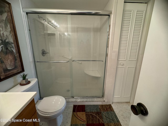 bathroom with toilet, tile patterned flooring, vanity, and a shower with door