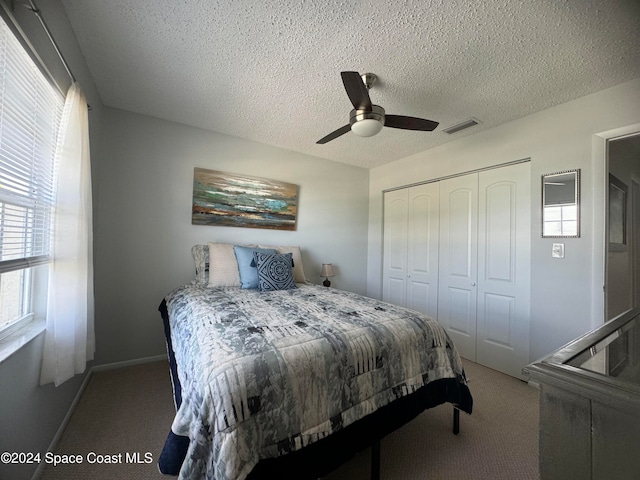 bedroom with a textured ceiling, carpet flooring, a closet, and ceiling fan