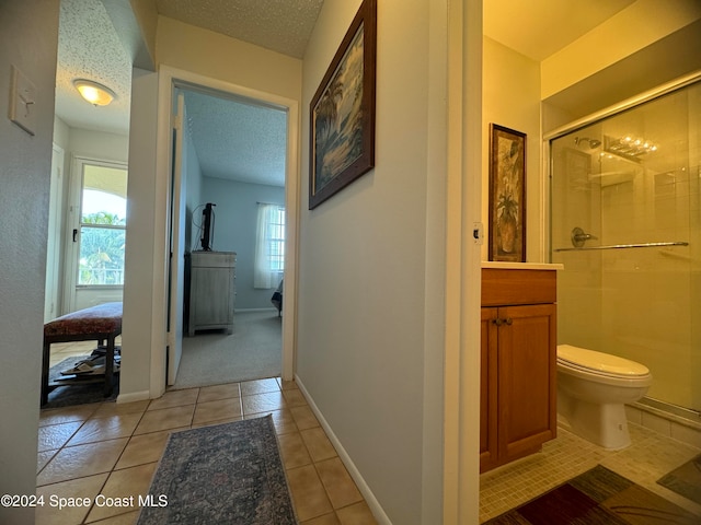 bathroom featuring a shower with shower door, a textured ceiling, toilet, and tile patterned flooring