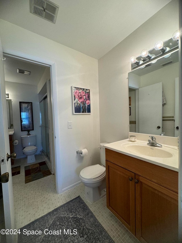 bathroom with toilet, vanity, a shower, and tile patterned flooring