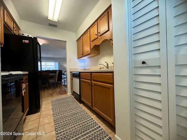 kitchen with dishwashing machine, black refrigerator, and light tile patterned floors