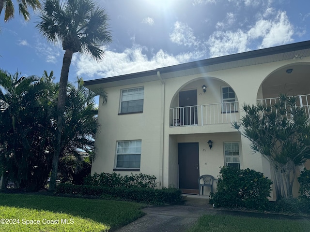 view of front of property with a balcony and a front lawn