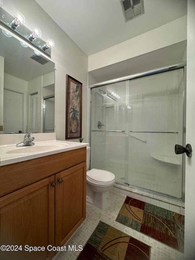 bathroom featuring vanity, a shower with shower door, toilet, and tile patterned floors