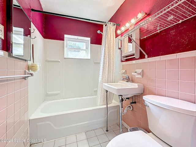 185 Richards Rd, Melbourne Beach, FL 32951 - bathroom with tile walls, tile patterned flooring, toilet, shower / bath combo with shower curtain, and a wainscoted wall