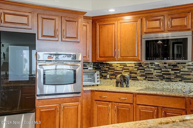 kitchen featuring light stone countertops, appliances with stainless steel finishes, and tasteful backsplash