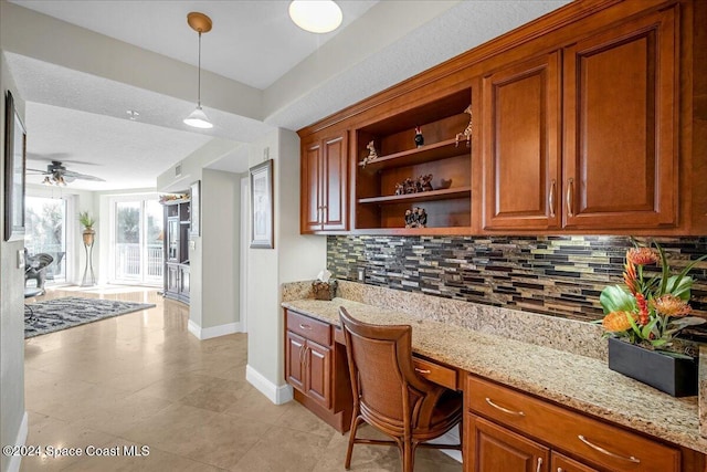 kitchen featuring built in desk, light stone counters, and backsplash