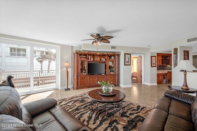 living room with ceiling fan and a textured ceiling