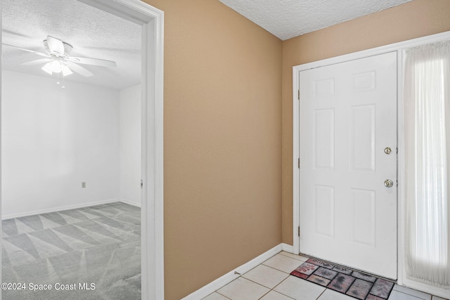 entrance foyer with light carpet, a textured ceiling, and ceiling fan