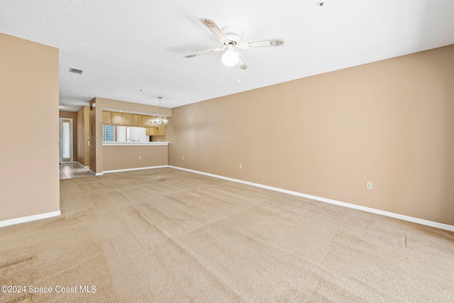 unfurnished room with light carpet, a textured ceiling, and ceiling fan with notable chandelier